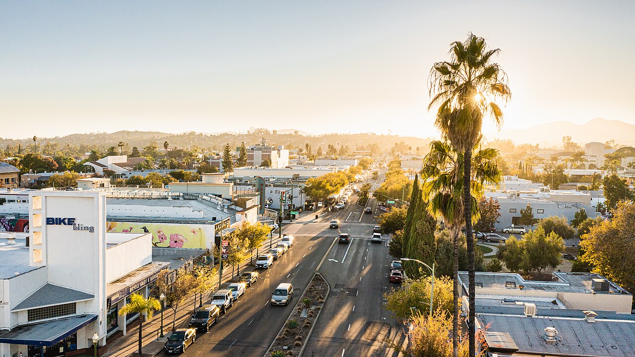 Aerial view over Grand Avenue in historic downtown Escondido, with streets, buildings, and hills in the distance.