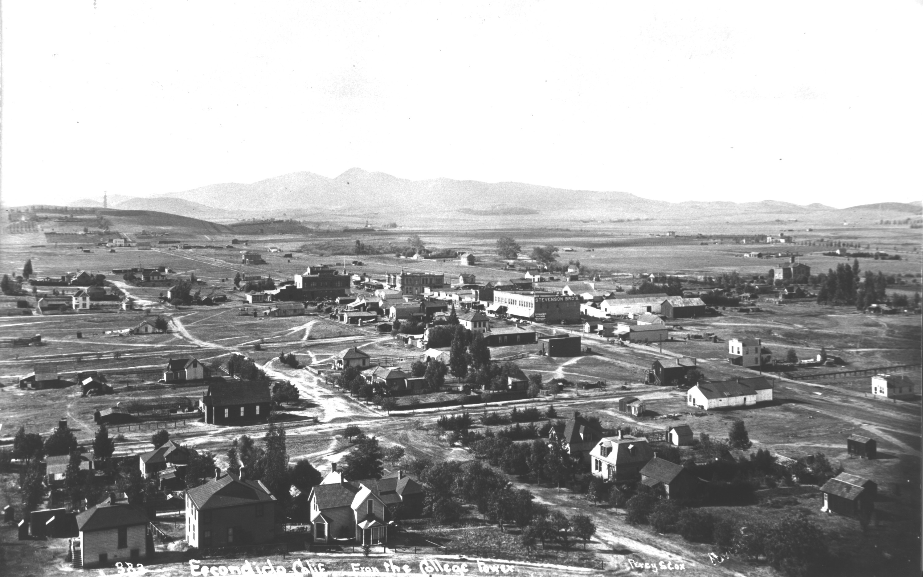An elevated black-and-white view across sparse buildings and roads in early Escondido.