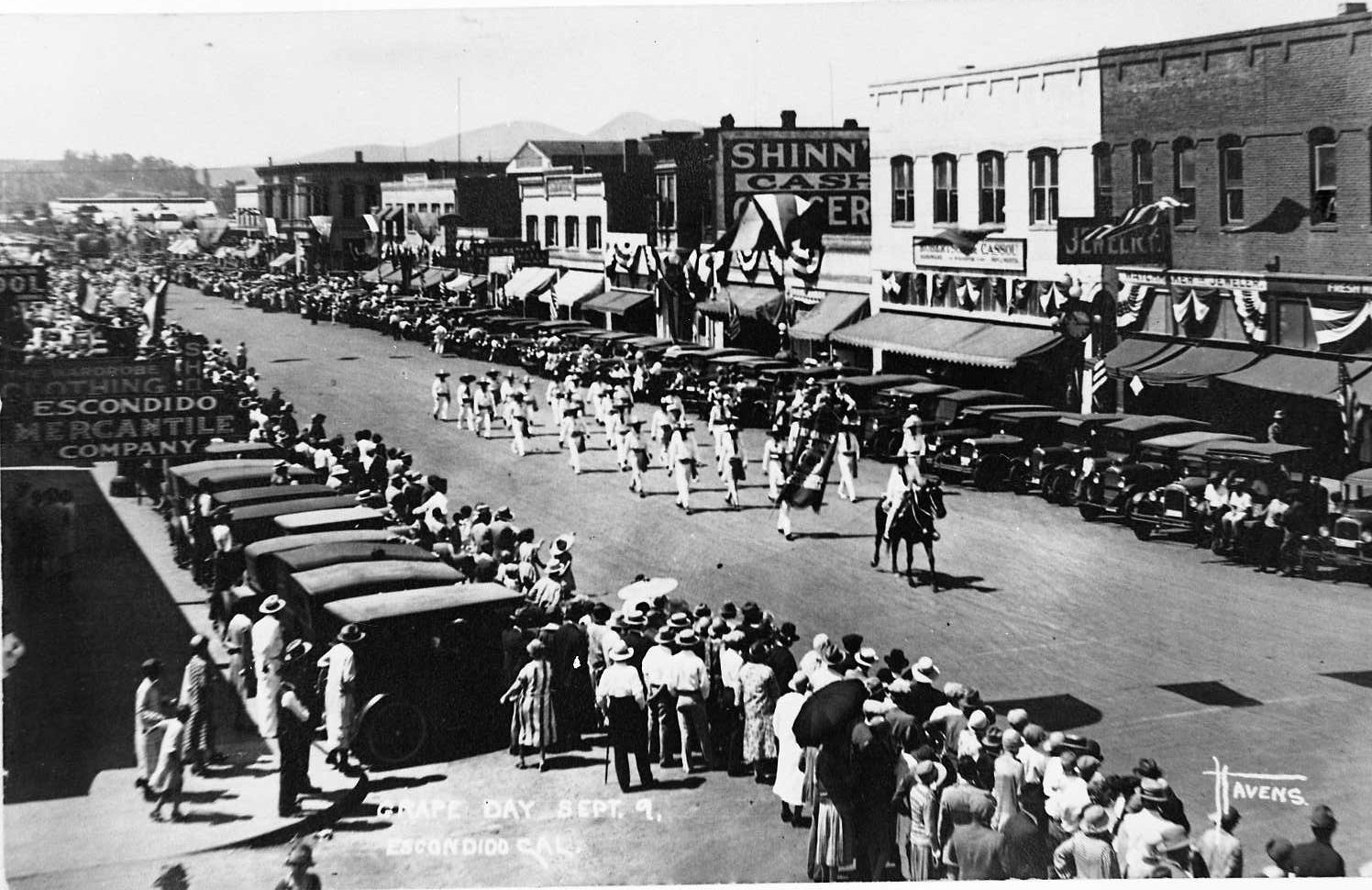 Crowds line historic Grand Avenue as decorated vehicles travel in a Grape Day parade.