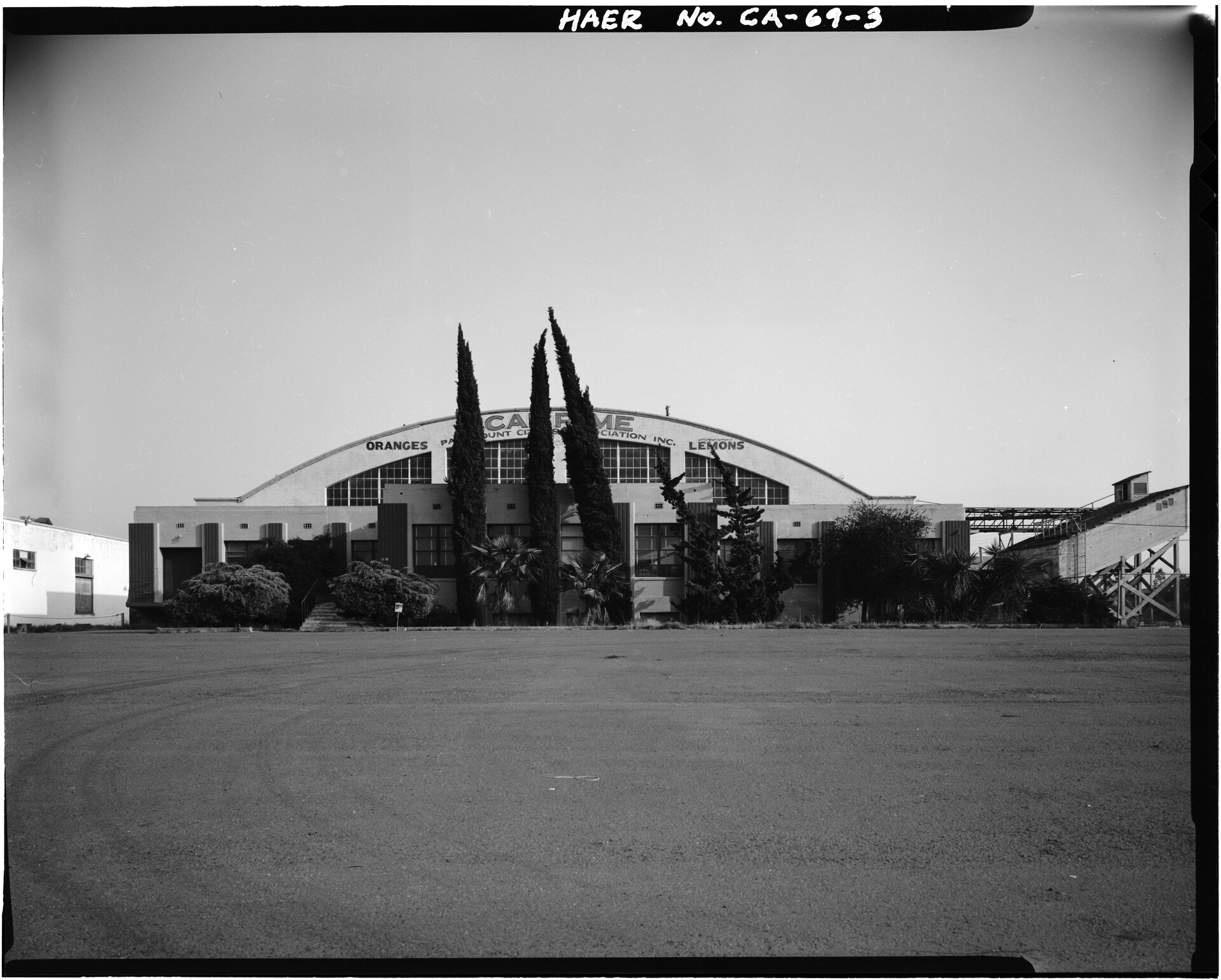 Black-and-white north-front exterior of the Escondido Orange Association Packing House, showing loading openings and painted signage.