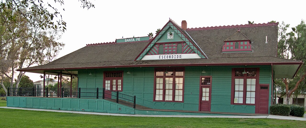 Historic Santa Fe train station building in Grape Day Park with trees nearby.